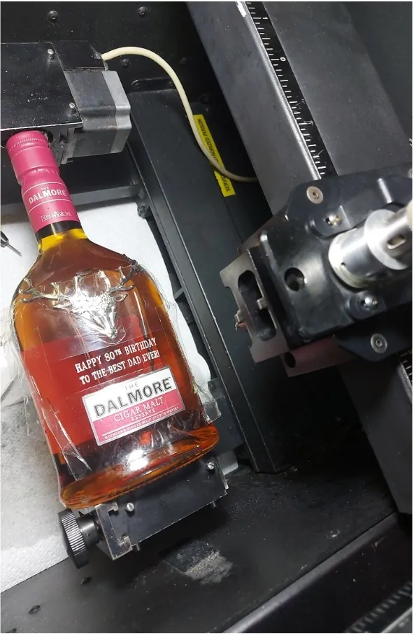 Whisky bottle clamped on the rotary engraving machine