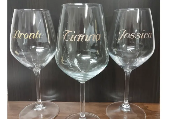 Three wine glasses engraved in script with the names Bronte, Tianna and Jessica